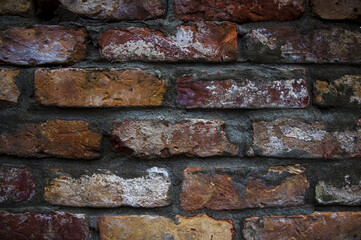Grey white black red orange old vintage brick wall background. Rustic cemented dark brick house wall texture with grunge surface. Shabby Building Facade With Damaged Plaster. Aged weathered exterior