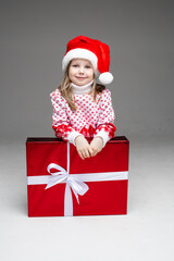 Adorable little girl in Santa hat with present.