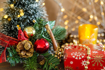 Close-up Christmas festive background with a Christmas tree decorated with decor balls with gold lights, boxes with gifts, candles on a wooden table close-up.