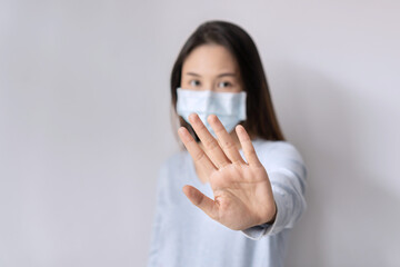 Stress young Asian woman wearing medical mask gesturing stop or say no on white background. Copy space, closeup