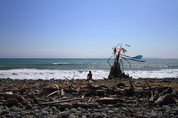 hippy on a sunny beach with wooden shelter teepee with ocean view on a windy day