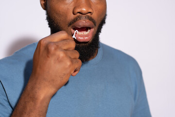 young black man using a floss to clean his teeth close up