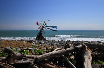 hippy on a sunny beach with wooden shelter teepee with ocean view on a windy day