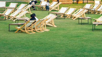 Asian young couple sit to relax and look at the menu to order food for dinner on white deck chairs...