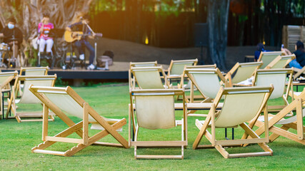 Many white deck chairs with tables for dinner in lawn is surrounded by shady green grass with...