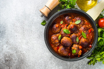 Meatballs in tomato sauce in a frying pan at light stone table. Top view copy space.
