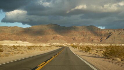 Road trip, driving auto from Death Valley to Las Vegas, Nevada USA. Hitchhiking traveling in America. Highway journey, dramatic atmosphere, sunset mountain and Mojave desert wilderness. View from car.