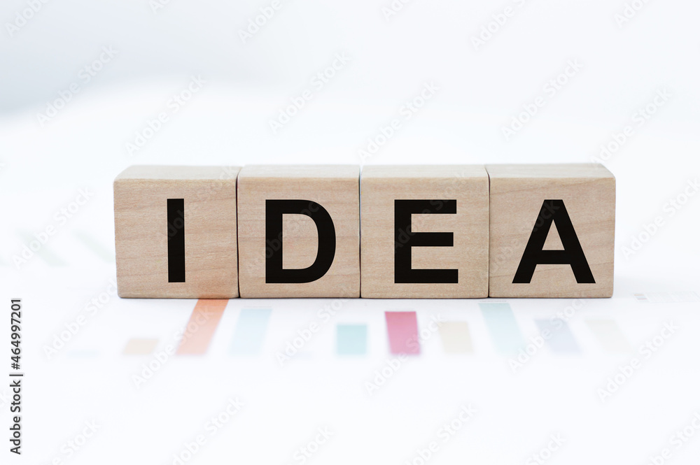 Poster wood cubes with idea text on the table against the background of financial charts