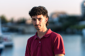 Young man with moustache and modern hair cut next to a river