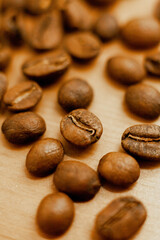 Roasted coffee beans are scattered on the table, the beans are lying on the table in a coffee shop, macro photos of coffee beans close to the face