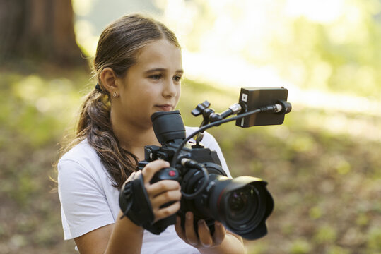 Cute girl shooting a video with a professional video camera