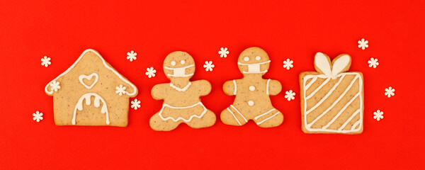 Happy New Year's 2022 set of gingerbread man in face mask from ginger biscuits glazed sugar icing decoration on classic traditional red background, minimal seasonal pandemic winter holiday banner