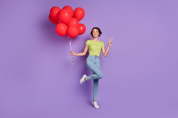 Fototapeta na wymiar Photo of attractive beautiful young lady wear green t-shirt showing v-sign holding red balloons isolated violet color background