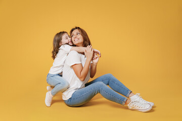 Full body length happy woman in basic white t-shirt have fun sit on floor child baby girl 5-6 years old Mom mum little kid daughter isolated on yellow color background studio Mother's Day love family.