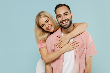 Young smiling happy cheerful couple two friends family man woman in casual clothes looking camera hug together isolated on pastel plain light blue background studio portrait People lifestyle concept.