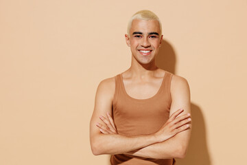 Young smiling fun happy blond latin american gay man with make up in beige tank shirt hold hands...