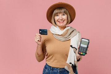 Traveler tourist mature woman 55 years old wears brown shirt hat hold wireless modern bank terminal...