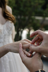 Obraz na płótnie Canvas Closeup of groom placing wedding ring on brides hand.