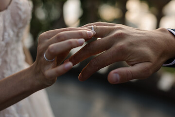 Closeup of groom placing wedding ring on brides hand.