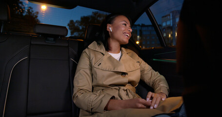 Happy woman in earphones sing song riding on backseat of car