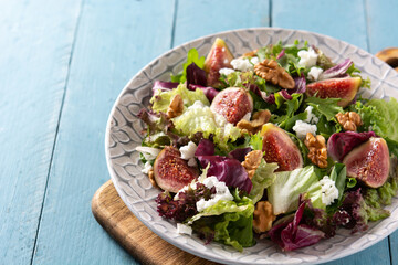 Figs salad with cheese and walnuts on blue wooden table	