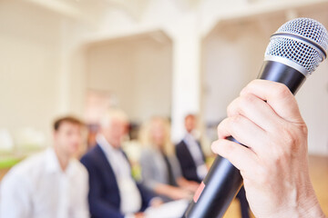Hand vom Redner hält ein Mikrofon bei einem Vortrag