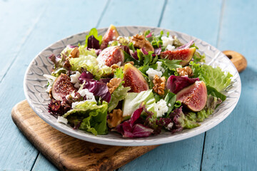 Figs salad with cheese and walnuts on blue wooden table	