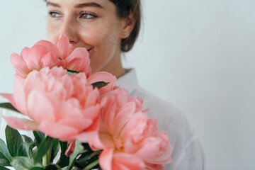 Happy woman smelling a bouquet of coral sunset peony