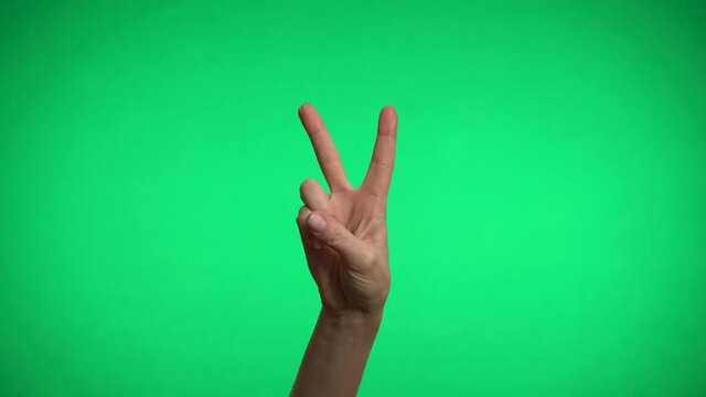 One hand on a green background shows the sign of peace.