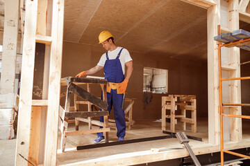 Male builder working at house building construction site