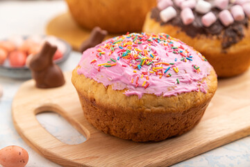 Homemade glazed and decorated easter pies with chocolate eggs and rabbits on a white concrete background. Side view, selective focus.