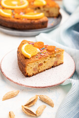 Orange cake with almonds and a cup of coffee on a white concrete background. Top view, selective focus.