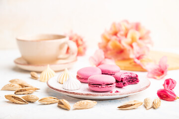 Fototapeta na wymiar Purple macarons or macaroons cakes with cup of coffee on a white concrete background. Side view, close up, selective focus.