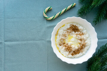 Christmas rice porridge with butter and cinnamon on blue textile background, space for text