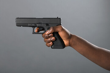 Hand of a Black man holding a handgun taking aim