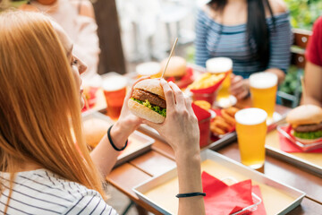 Woman with burger having lunch with friends