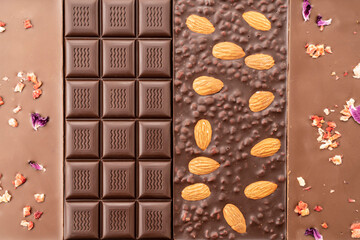 assortment chocolate bars with almonds, raspberries, handmade sweets. Composition of bars milk and dark almond chocolate, raspberries on a black background, top view. Pastry craft on the table