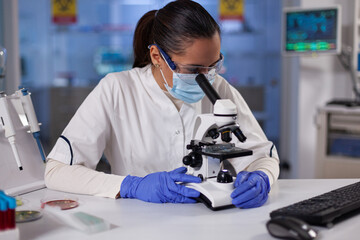 Specialist researcher analyzing genetic sample using medical microscope during biochemical...