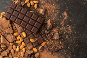 Store Cooking chocolate bars with almonds handmade sweets. Composition of bars and pieces of dark almond chocolate on a black background, top view. Pastry craft on the table