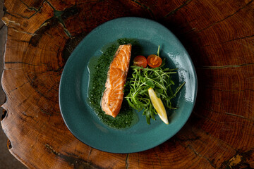 Healthy salmon and salad meal on a wide turquoise plate