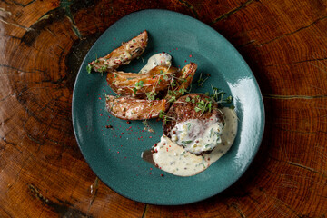 Beef steak with baked spicy potato wedges and tartar sauce, small single portion on a bright plate