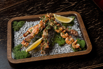 Modern fusion cuisine with spectacular serving, grilled prawns and salmon kebab on wooden skewers