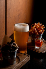 Cheese sticks with cranberry sauce and a full glass of light beer, soft light, dark atmosphere