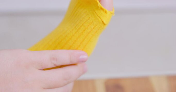 Mature man dressed in blue jeans puts IN order and pulls bright yellow sock with large hole hastily to hide problem macro
