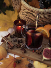 Close up of autumn picnic with food, mulled wine with cinnamon and chocolate on lawn with maple leaves in garden