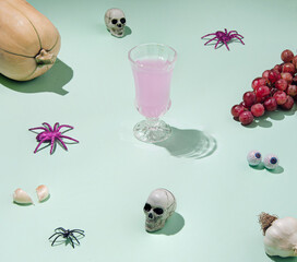 Creative spooky Halloween idea with skull, spider, and pumpkin on a mint green background. Colorful autumn concept.