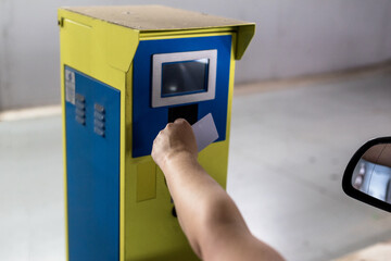 A woman's hand at the entrance of a parking lot brings a soft card to the sensor of the access machine to enter.
