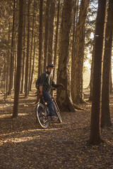 Fototapeta na wymiar A young man in a helmet on a sports bike in the forest, illuminated by sunlight.