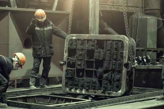 Workers in work with mold after metal casting in steel mill foundry.