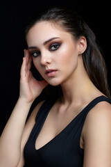 Beauty portrait of young woman. Brunette girl with evening female makeup and black dress